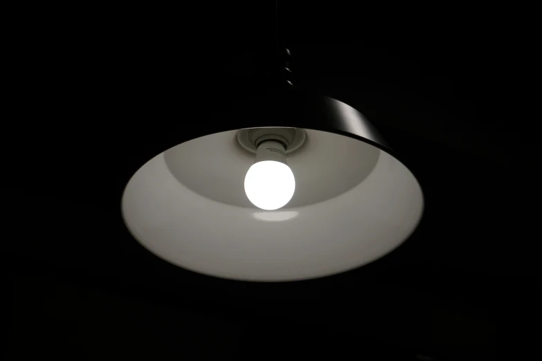 an illuminated ceiling lamp sits over a black room