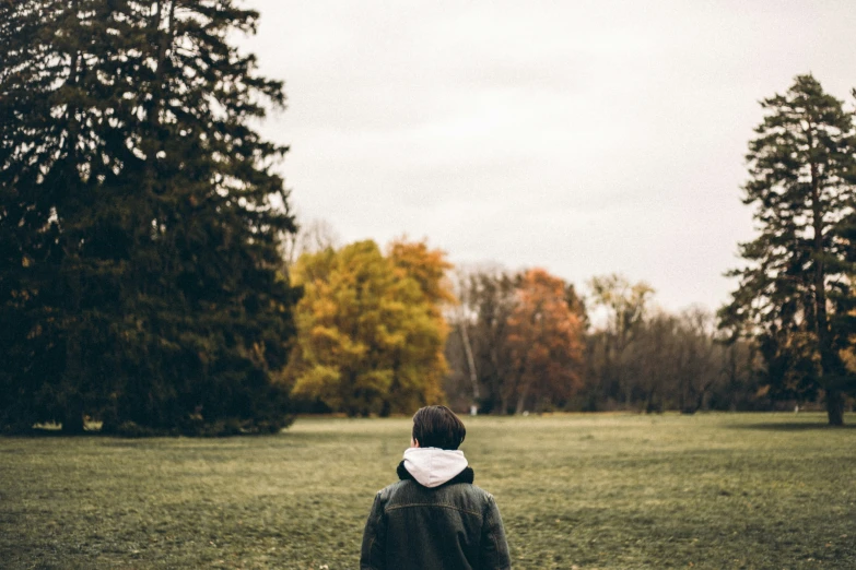 a man standing on a lush green field next to trees