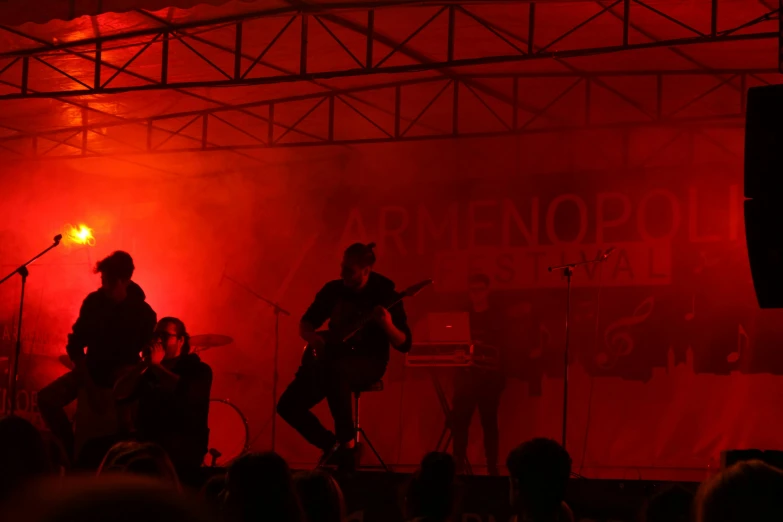 two musicians perform at an event with red lights behind them