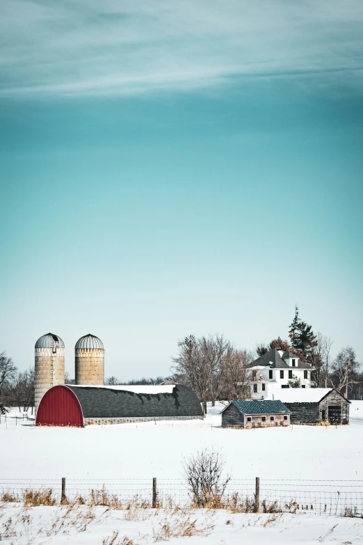 snow covers a field behind a large barn