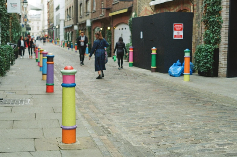 a city sidewalk with tall columns painted in various colors