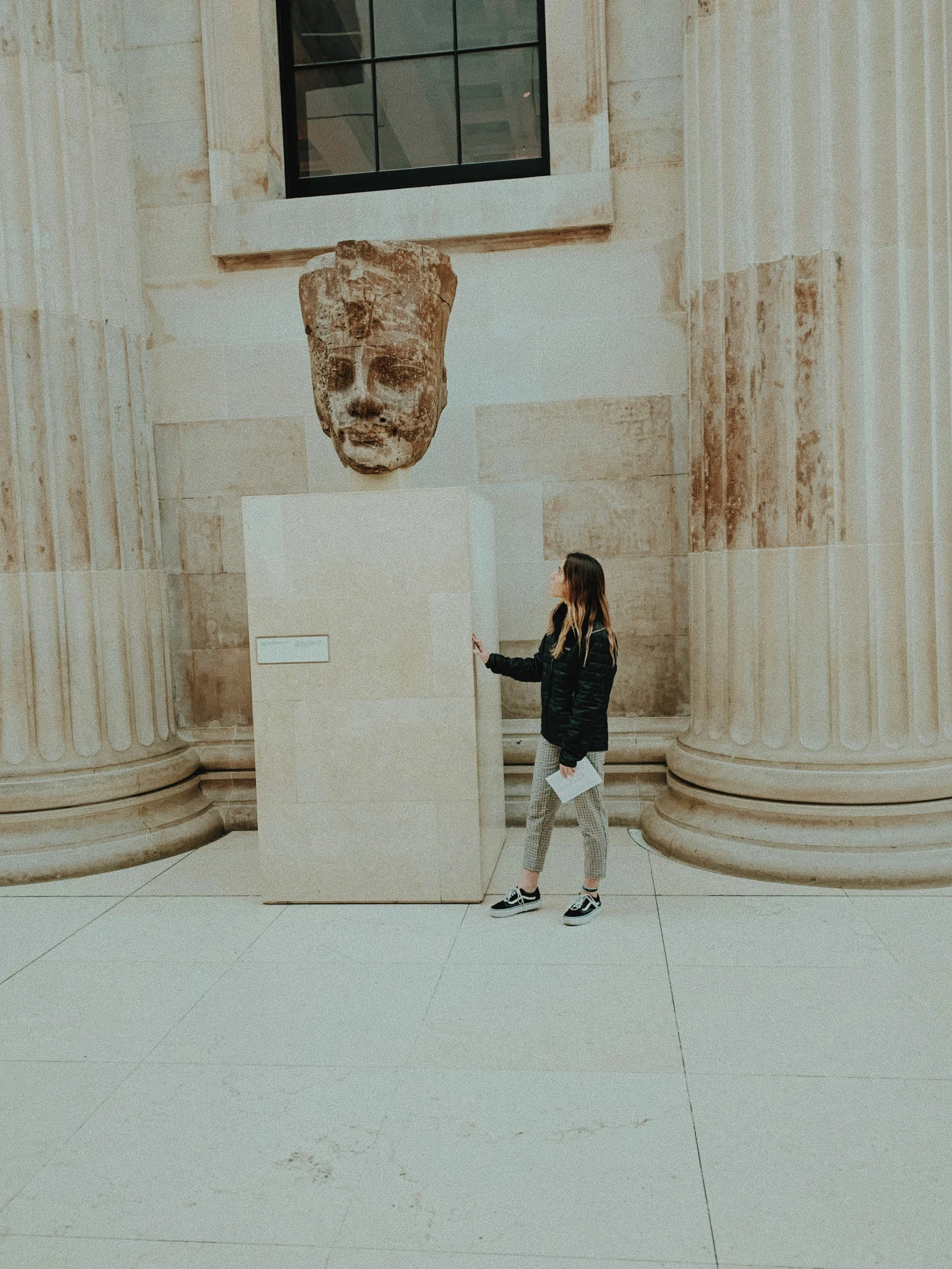 a young woman in black jacket next to some stone pillars