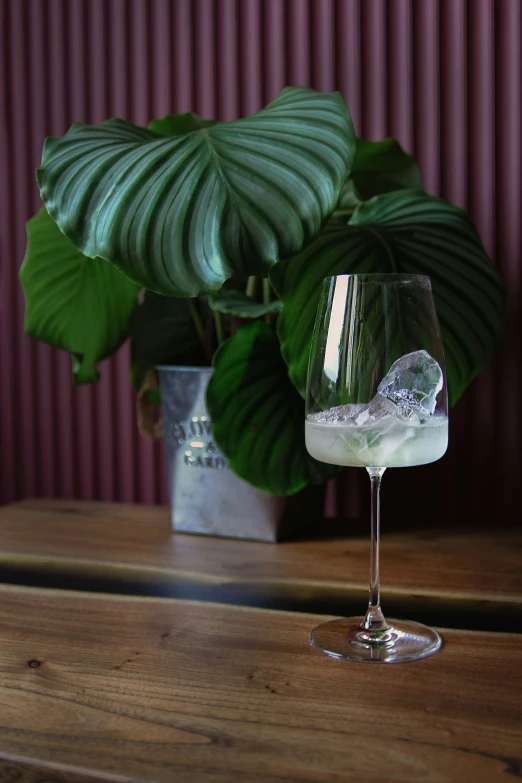 a cocktail glass filled with liquid and ice sits on a table