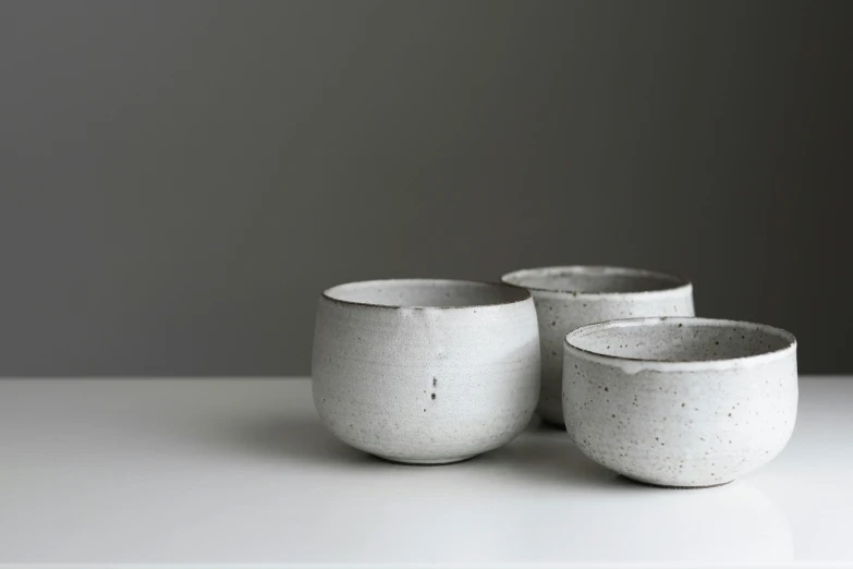 three white cups sitting on a counter with dark gray background