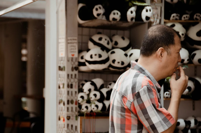 a man talking on his cell phone in front of a rack of panda masks