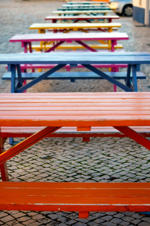 several brightly colored picnic benches are on a brick walkway