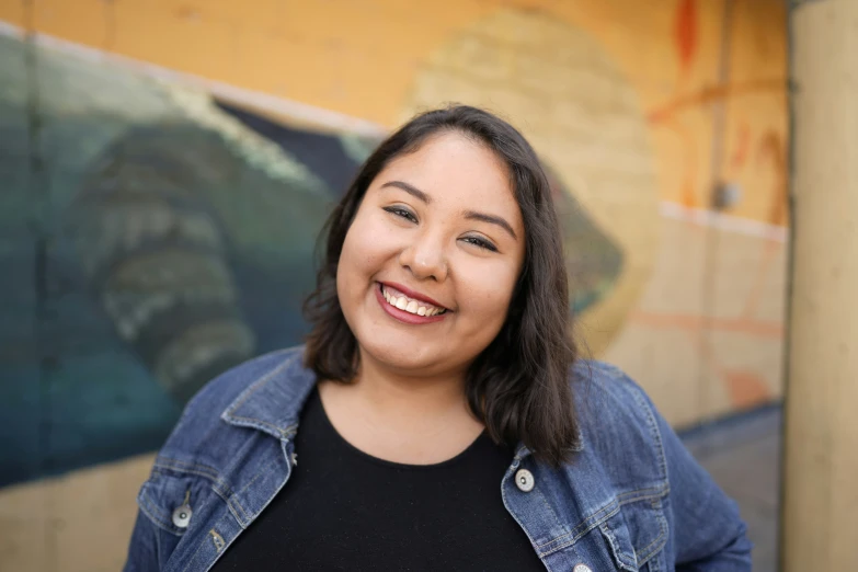 a woman stands in front of a large, colorful background