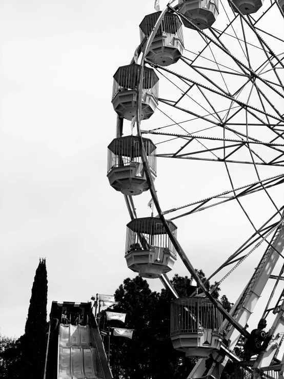 an upside down ferris wheel with a grey sky behind it