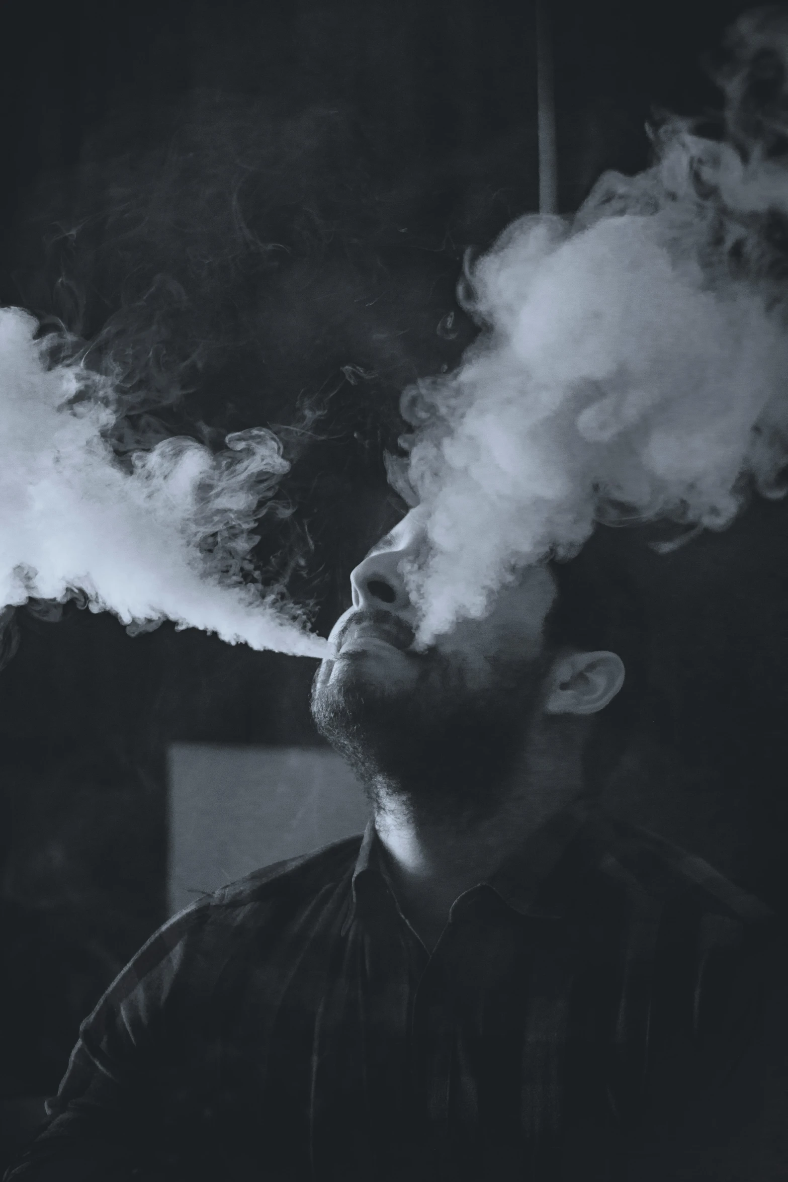 a man smoking a cigarette while standing in front of a light