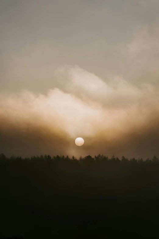 the sun shining through the clouds over the trees