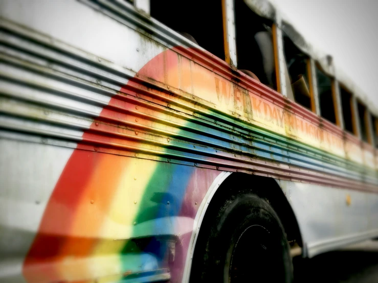 a rainbow painted bus with wheels