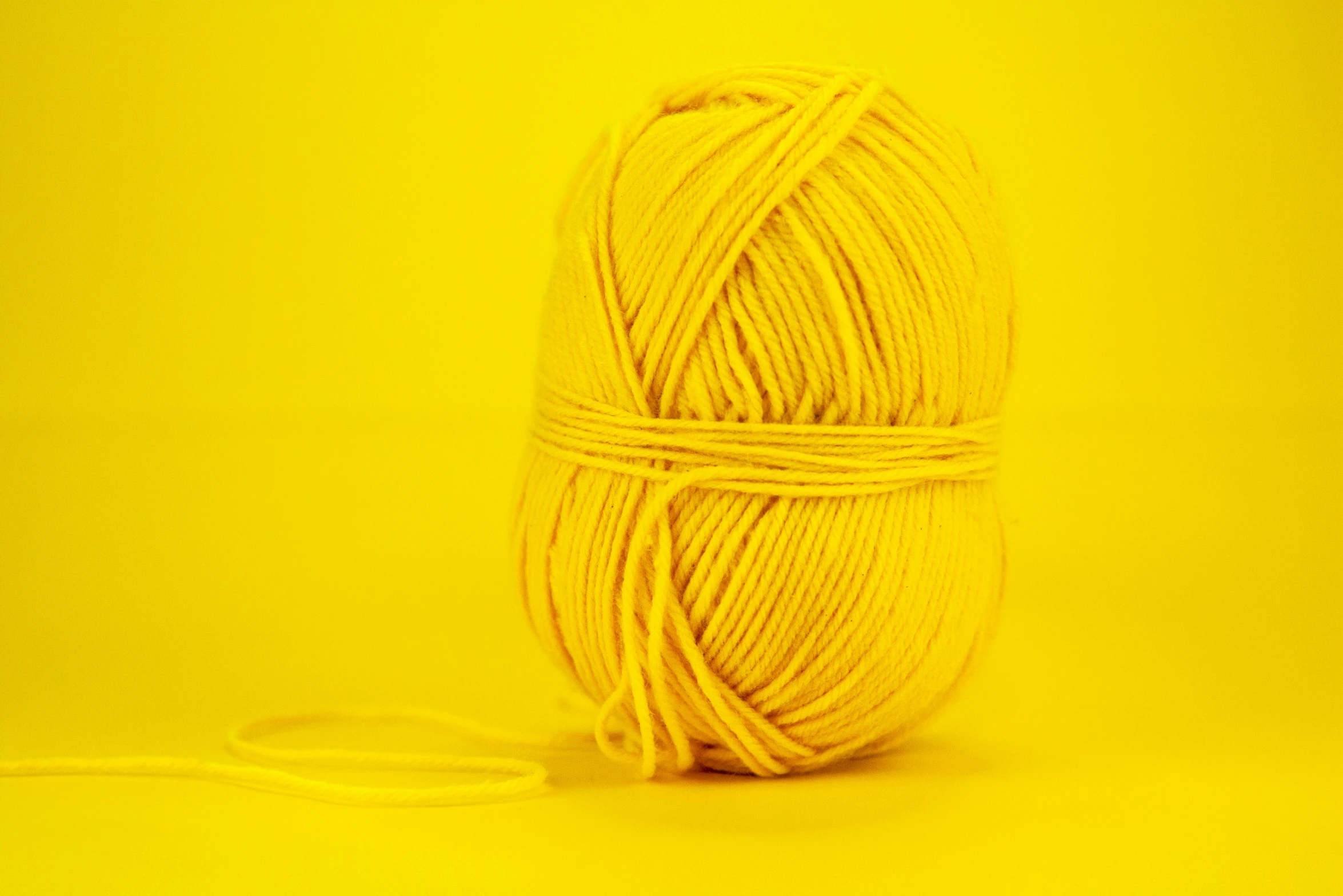 a yellow ball of yarn with a string in front of it