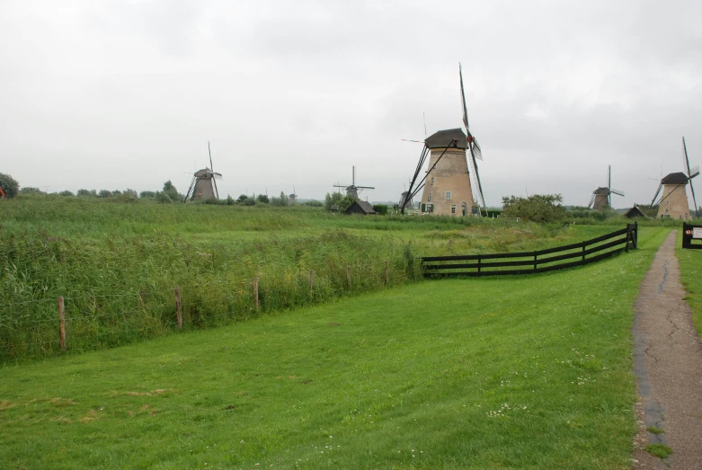 several windmills stand in a field near a road