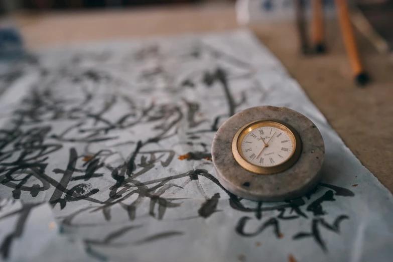 a clock and calligraphy on a blanket on the ground