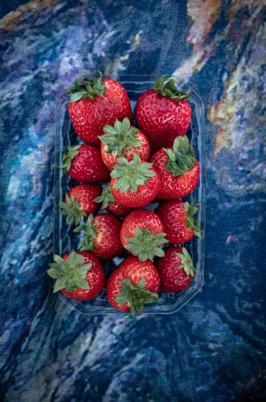 a container full of ripe strawberries sitting on top of a table