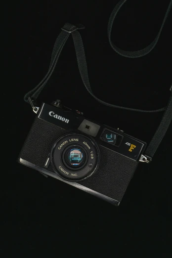 a canon camera on a black cloth with a black strap