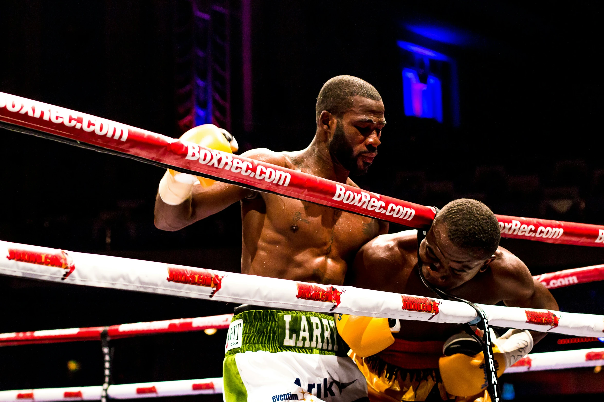 one boxer has his feet on the ropes and another is holding a boxing glove