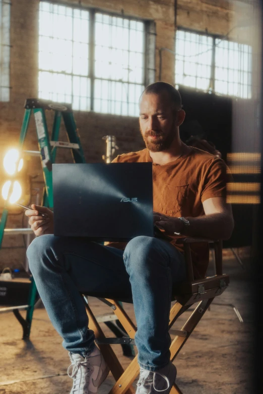 a man in a chair sits while using a laptop