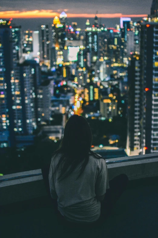 a person sitting on a ledge looking out at the city