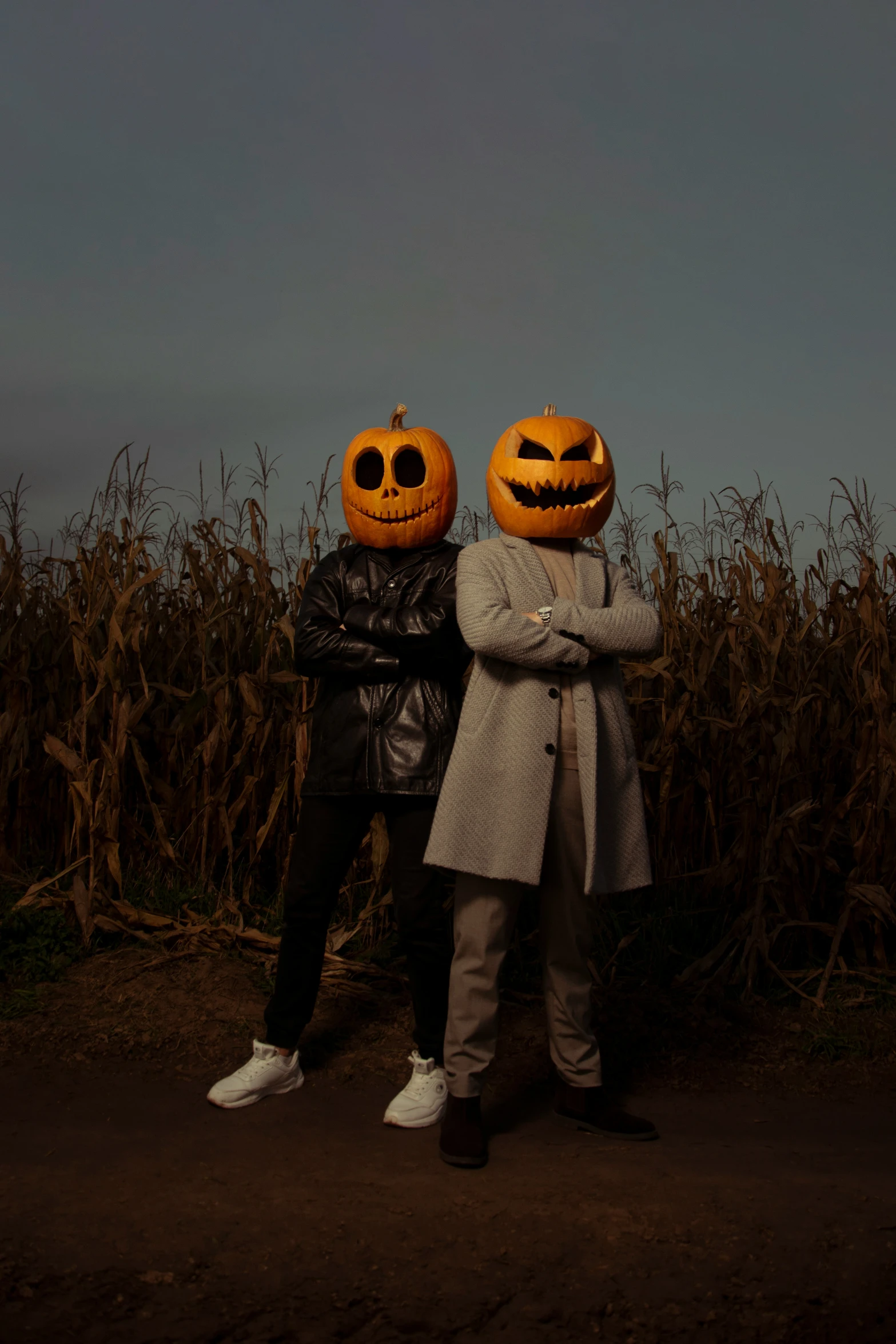 two people wearing jack o lanterns near a cornfield