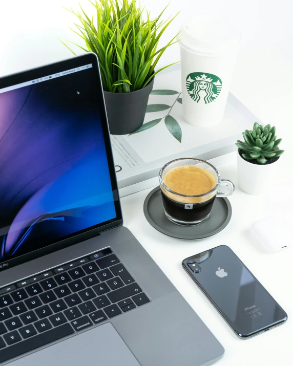 a laptop, mouse and cell phone sit on a desk