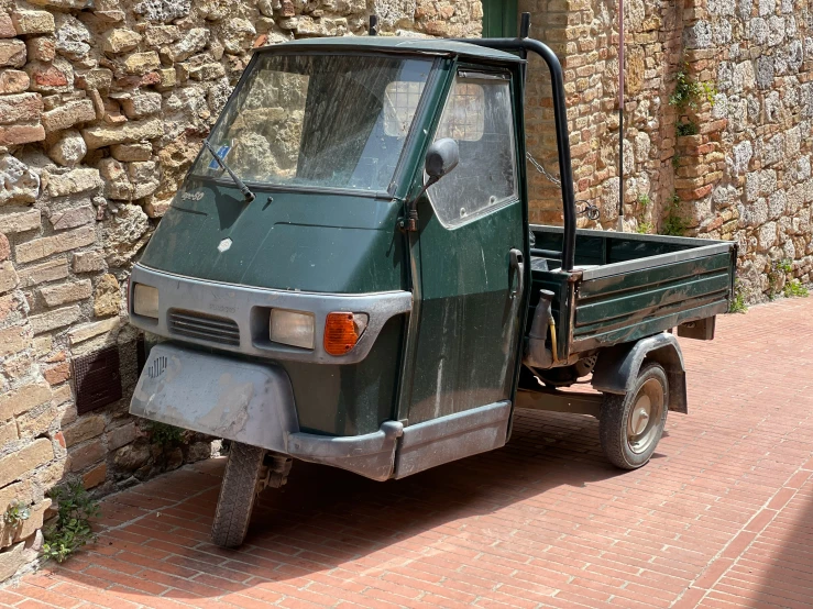 a green truck parked against a brick wall