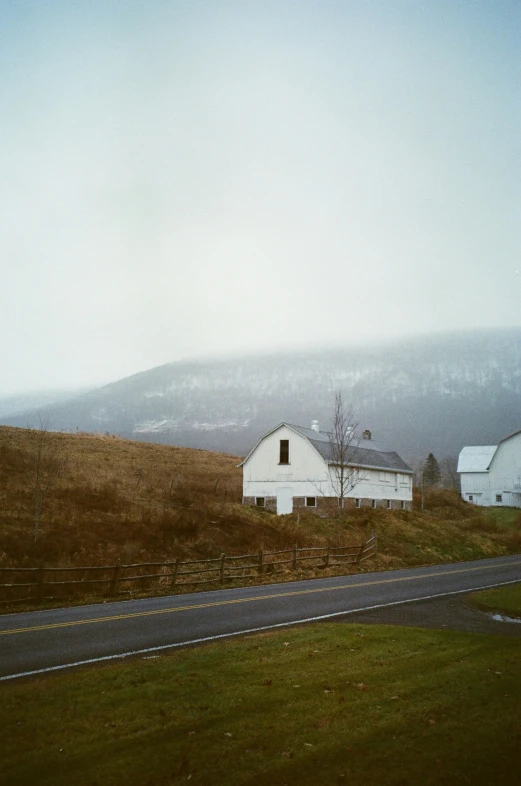 a farm with a barn and a road near a hill