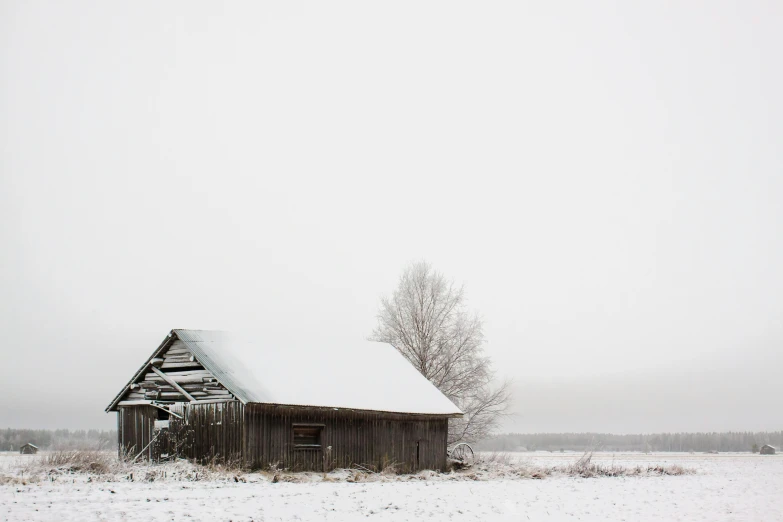 an old barn sitting in a snowy field