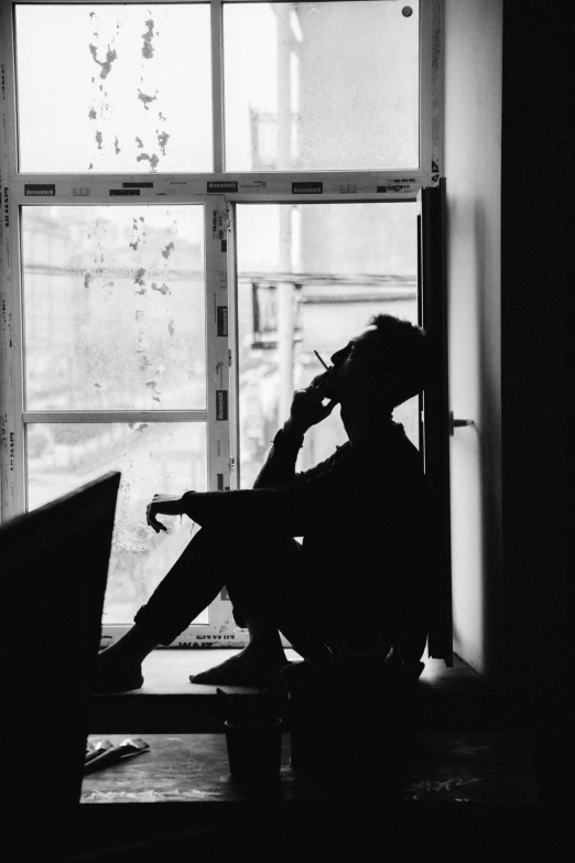 black and white po of a person sitting in front of a window