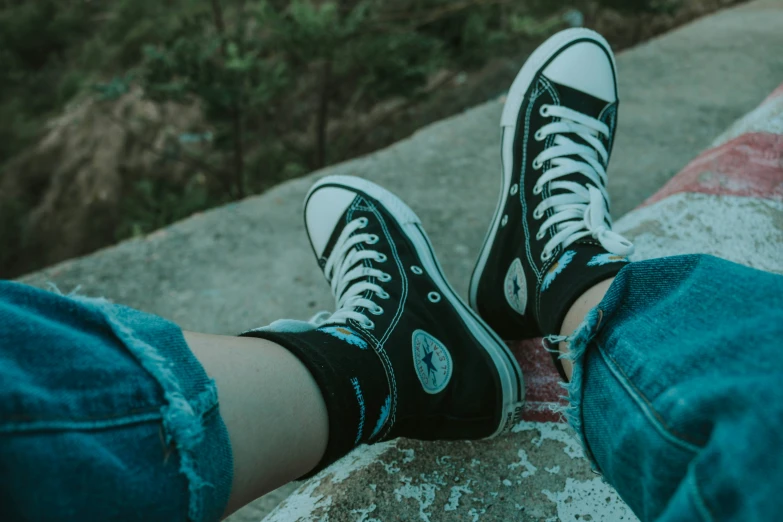a person is sitting on a bench wearing converse shoes