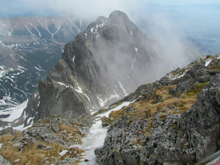 clouds hovering over a rocky terrain with mountain range in the background