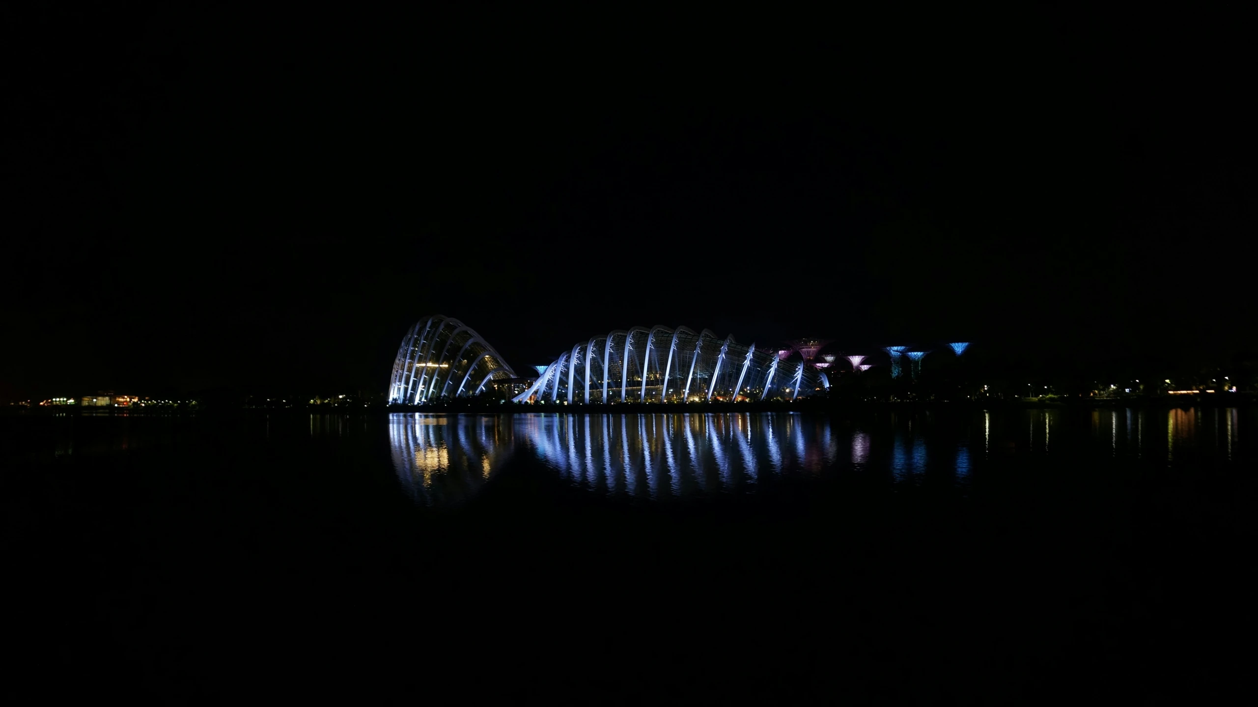 a large, futuristic building at night with reflections on the water