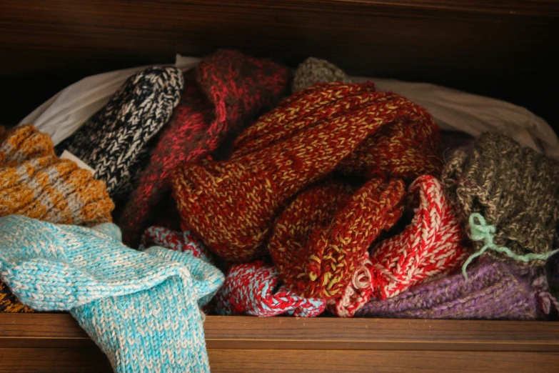 knitted scarves are stacked in a bin