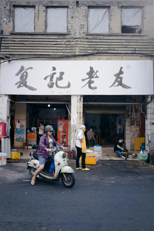 a man riding a motor scooter down the street