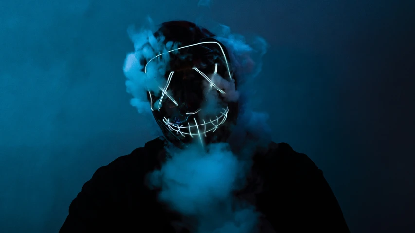 a person wearing a mask and smoke is shown with their face obscured in the fog
