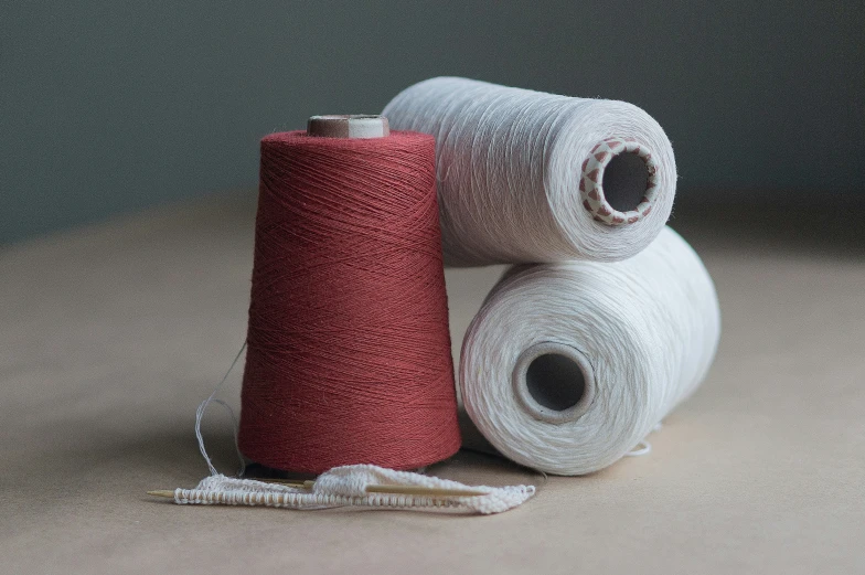 two red and one white yarn on a table