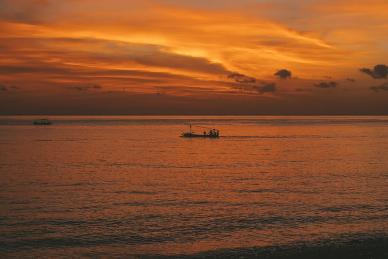 two boats out on a lake with a sunset behind them