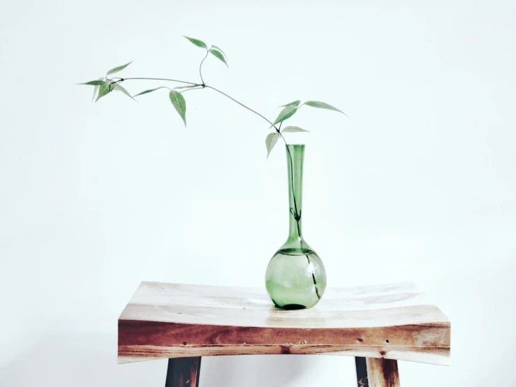 a green vase filled with water sitting on top of a wooden table