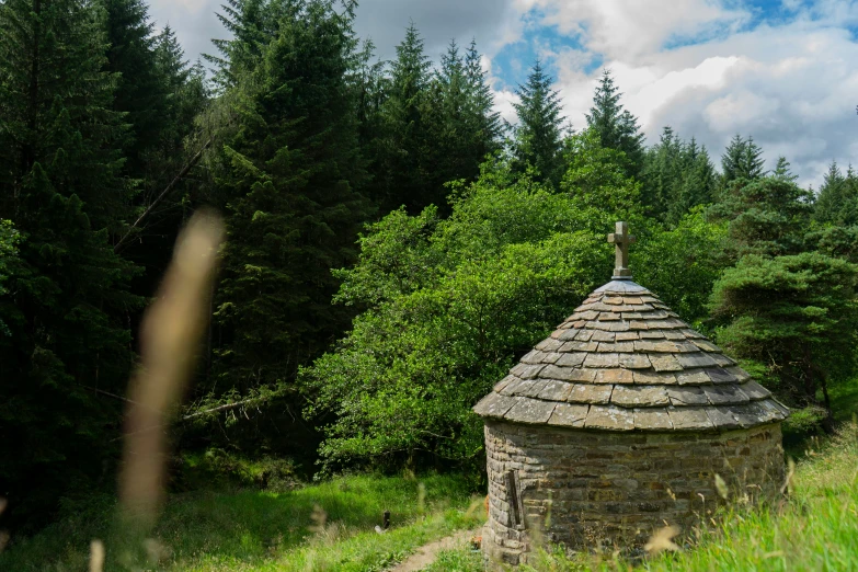 small stone structure in a forest with a pathway and trees