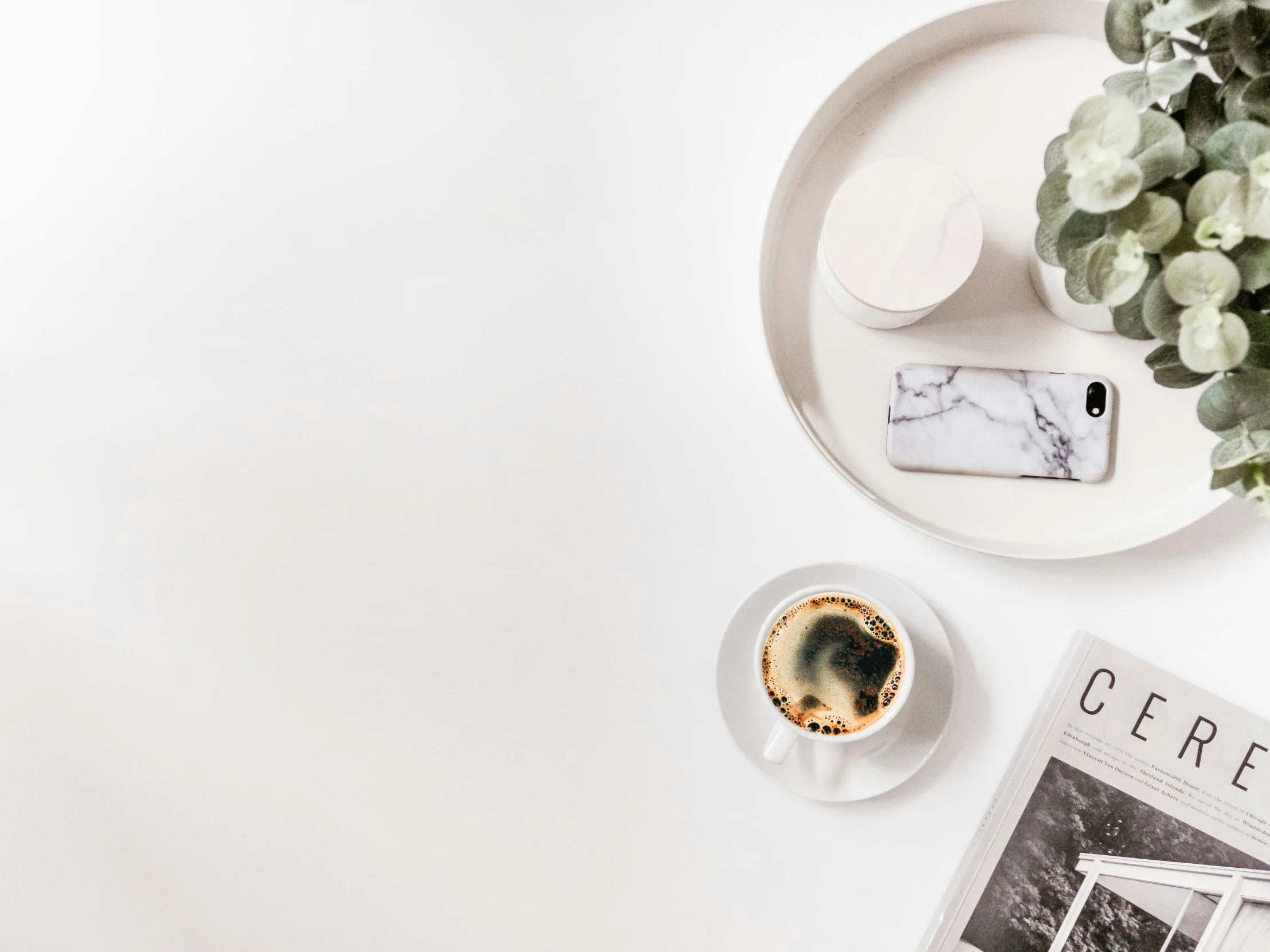 a cell phone and cup of coffee sit on top of a table