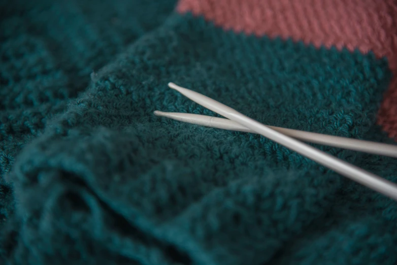 two knitting needles are in a blue sweater