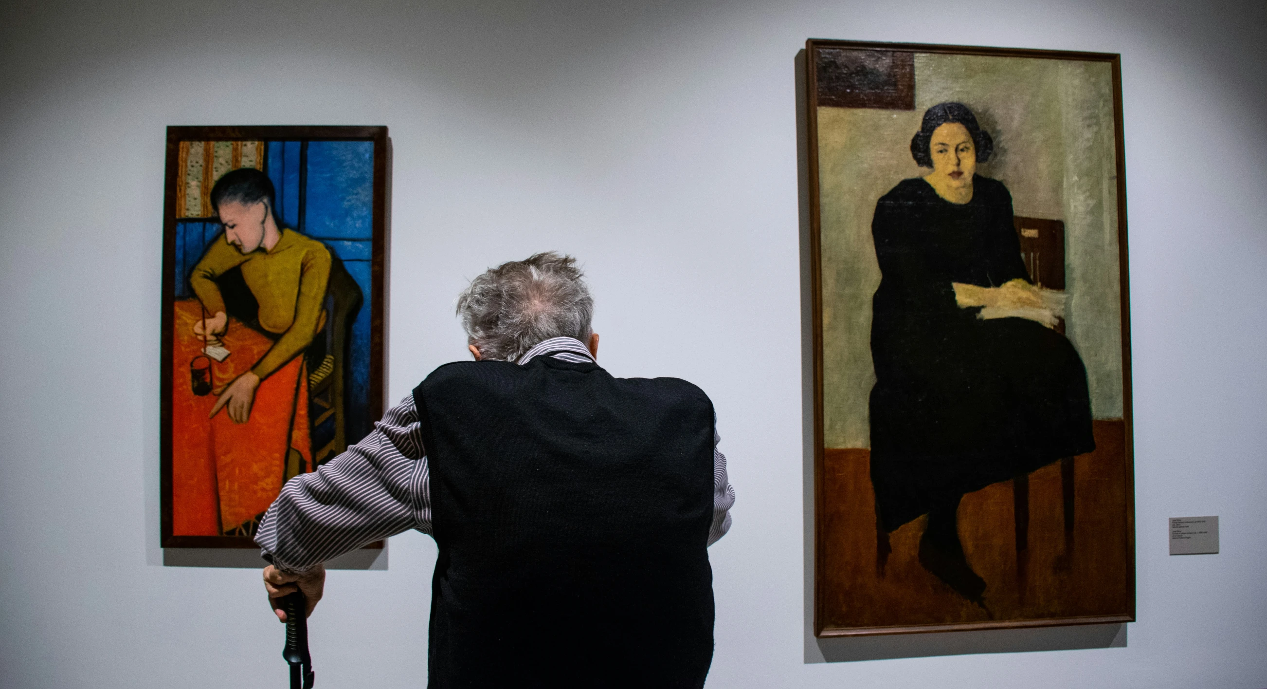 woman in black jacket observing some paintings