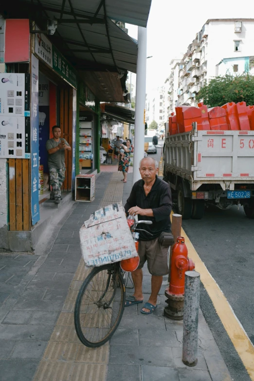 an old man riding a bike with a cart full of boxes on the back