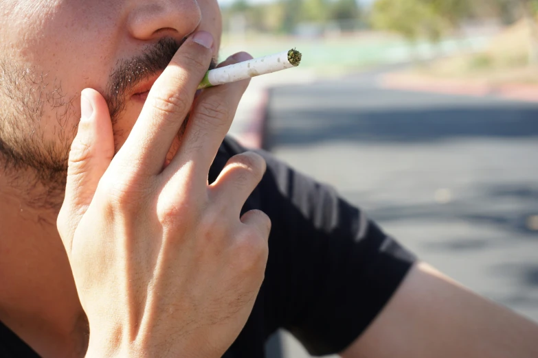 a man that is holding a cigarette to his mouth