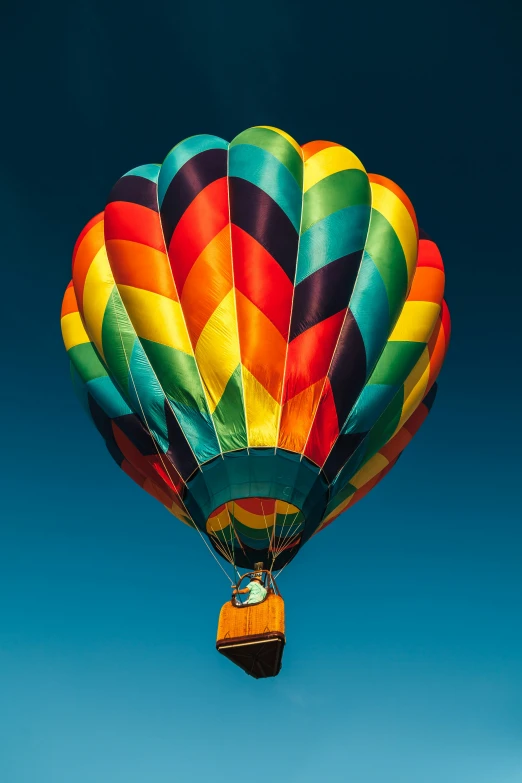 a multicolored  air balloon floating up in the sky