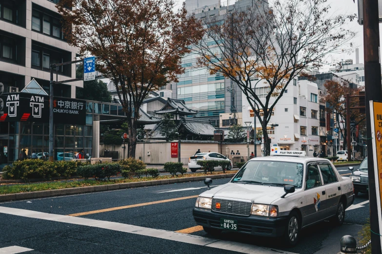 cars driving down the street at a crosswalk with tall buildings