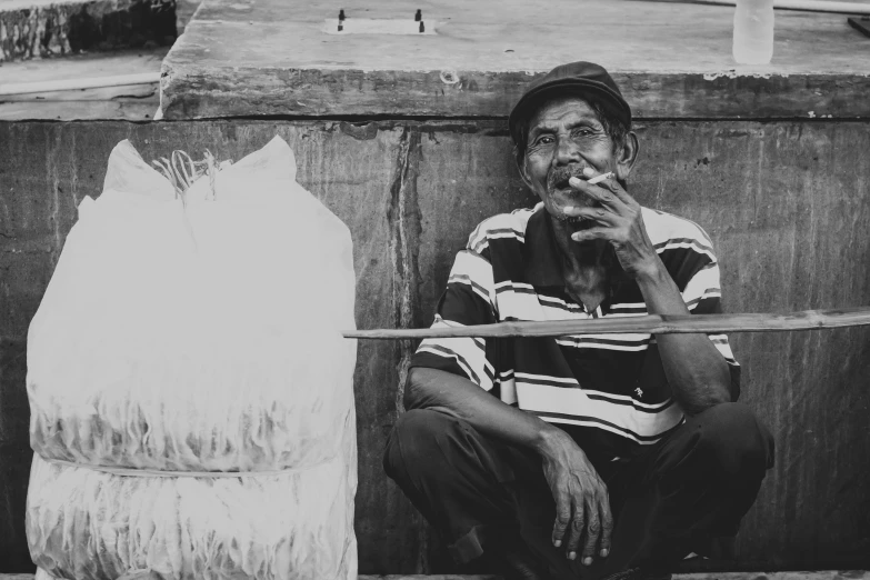 the man is smoking while sitting on the ground