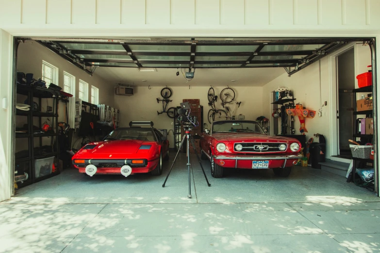 two red mustang cars parked in a garage