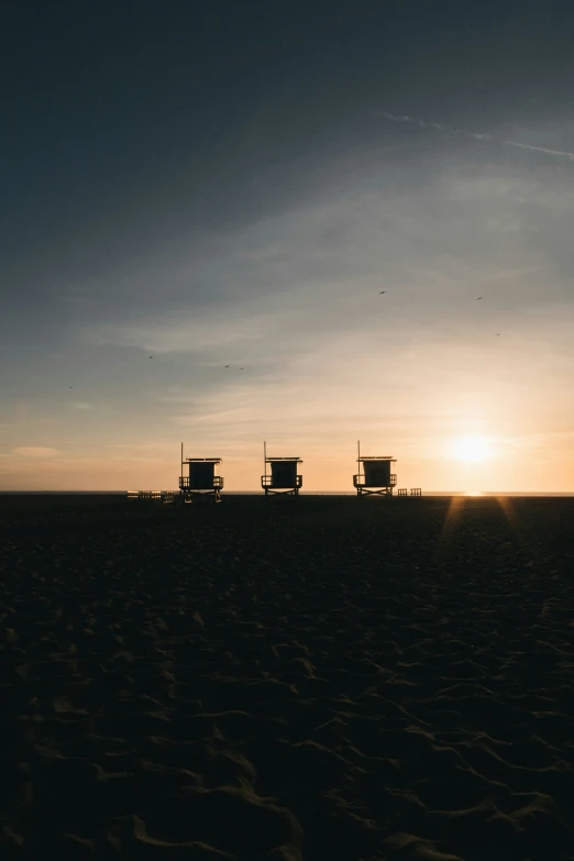 three empty chairs sitting on a beach in the sun