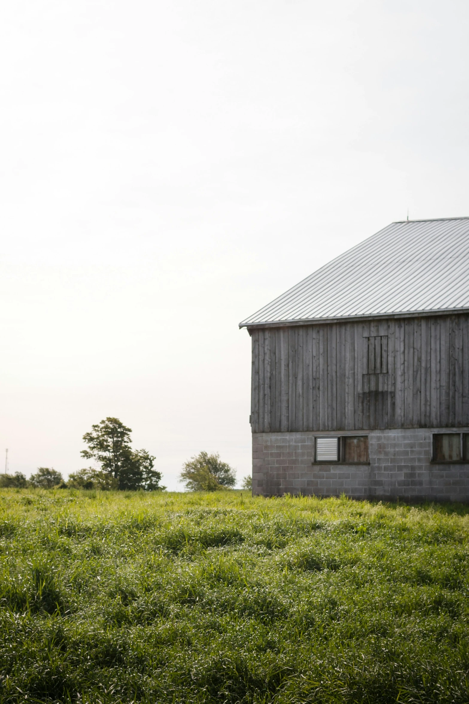 an old barn stands in a large field